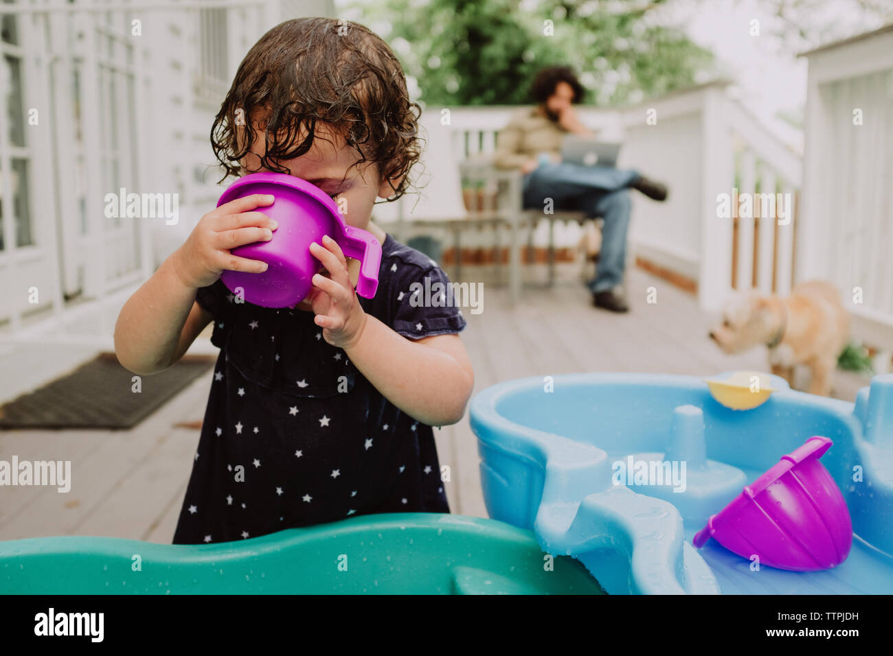 Ragazza che gioca con i giocattoli di acqua mentre il padre lavora in  background Foto stock - Alamy
