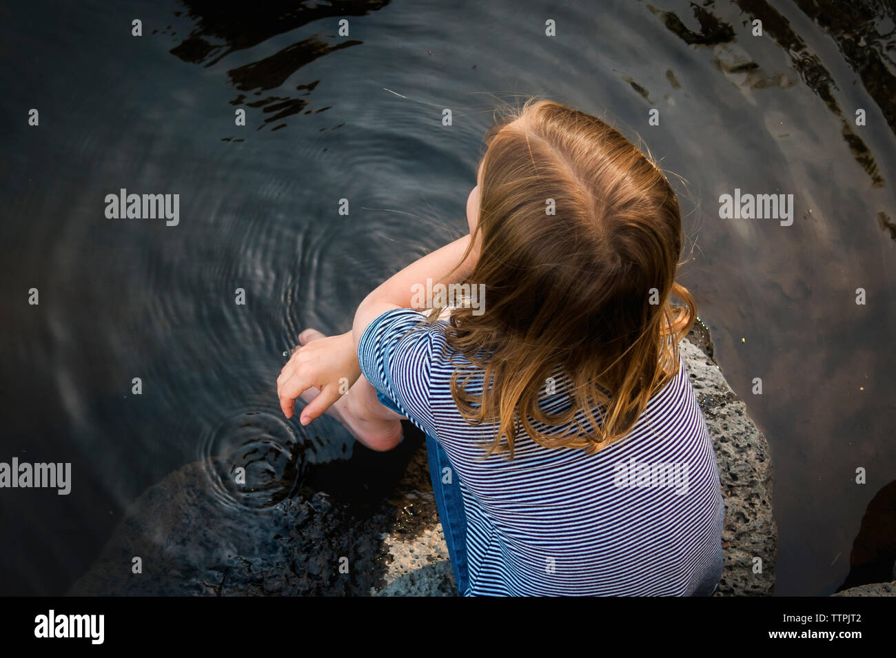 Vista aerea della ragazza seduta sulla roccia nel lago Foto Stock