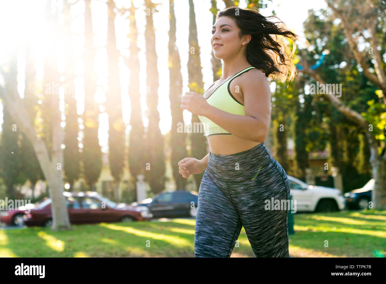 La donna a fare jogging nel parco durante la giornata di sole Foto Stock