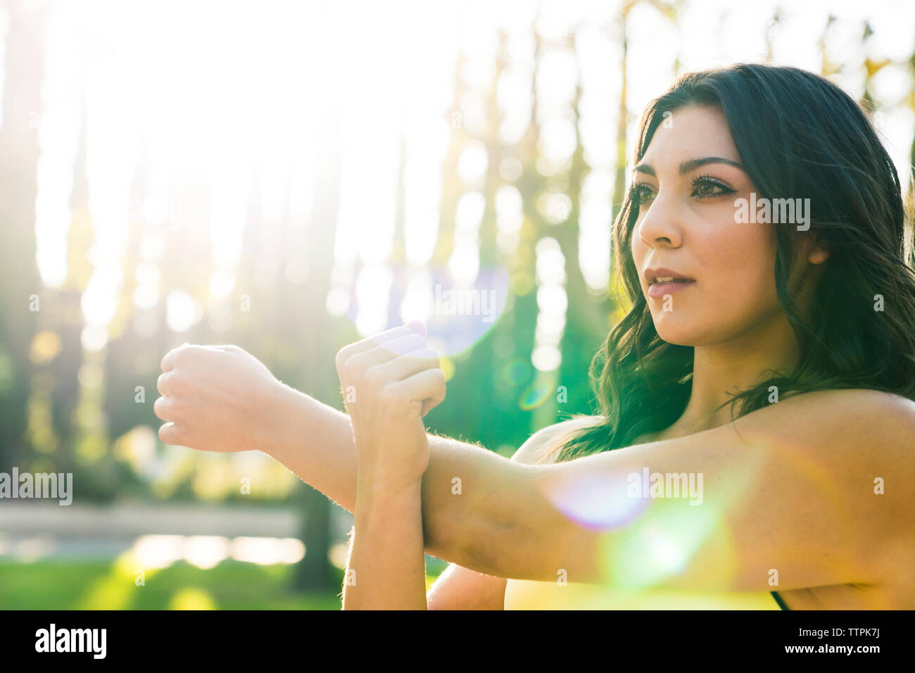 Donna braccio di allungamento permanente, mentre in posizione di stazionamento durante la giornata di sole Foto Stock