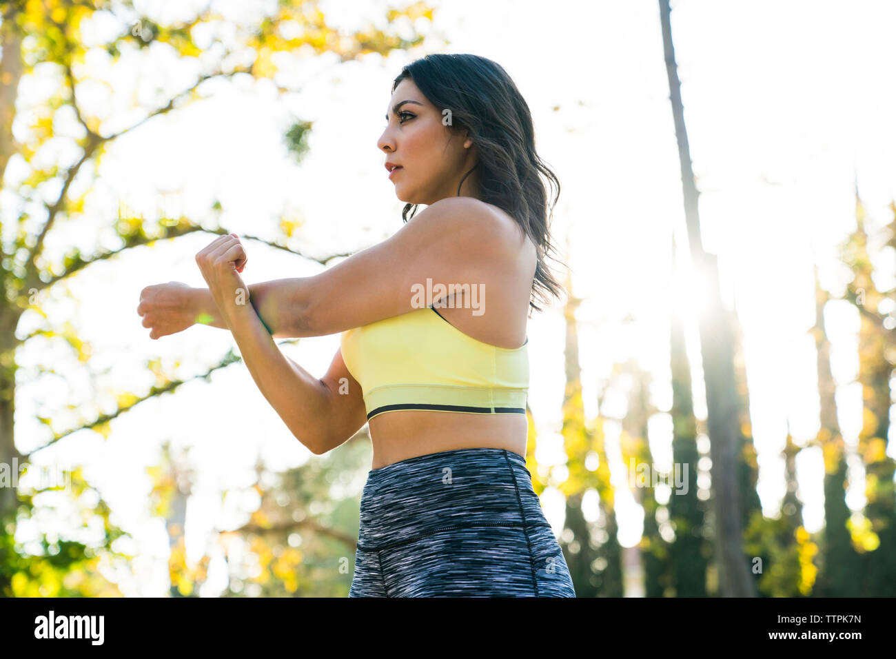 Basso angolo di visione della donna gravi braccio di allungamento permanente, mentre in posizione di parcheggio Foto Stock