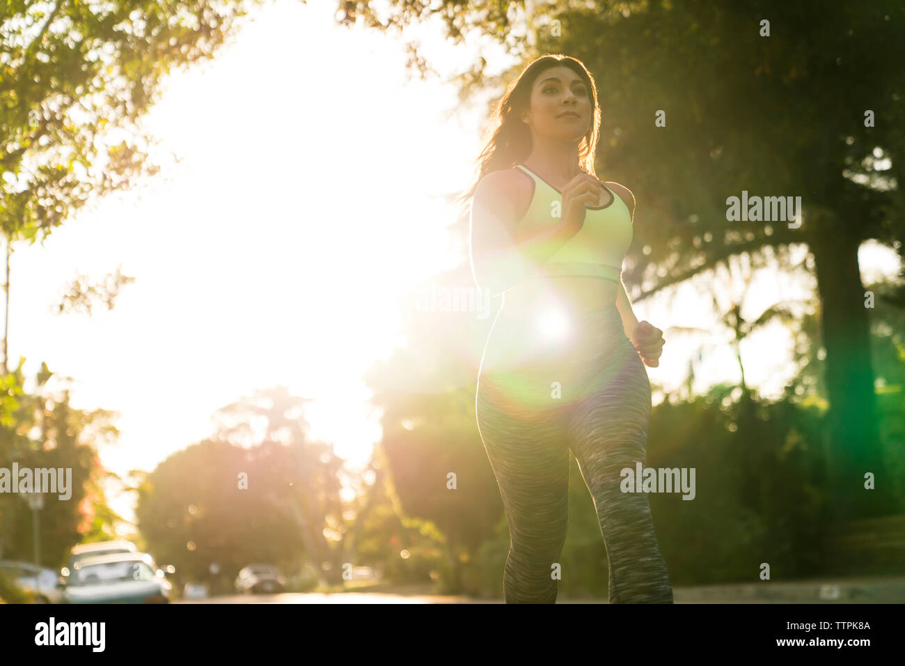 Basso angolo di visione della donna a fare jogging nel parco durante la giornata di sole Foto Stock