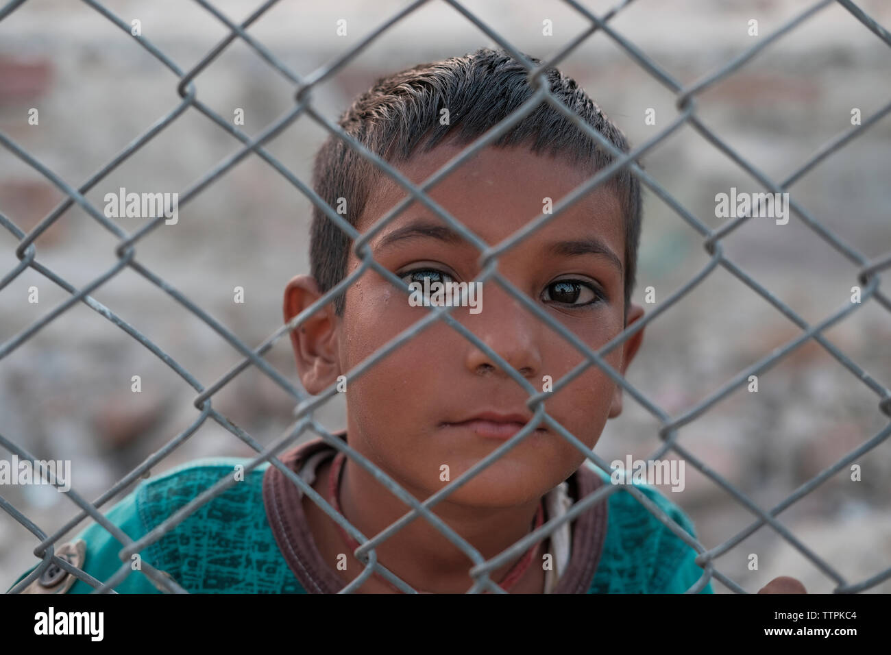 Ritratto di ragazzo visto attraverso la recinzione ad anelli in città Foto Stock