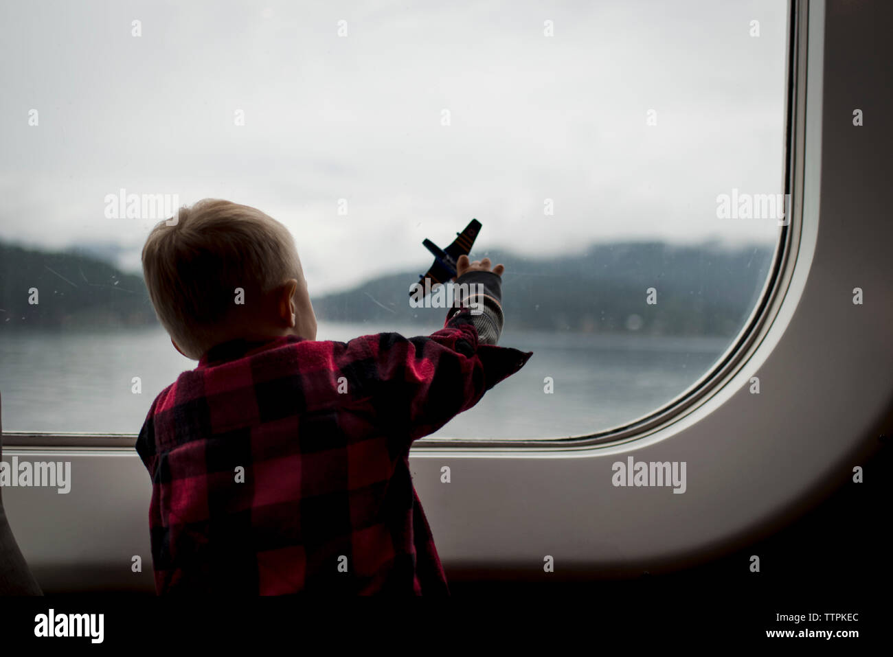 Vista posteriore del ragazzo giocando con Toy piano durante il viaggio in treno Foto Stock