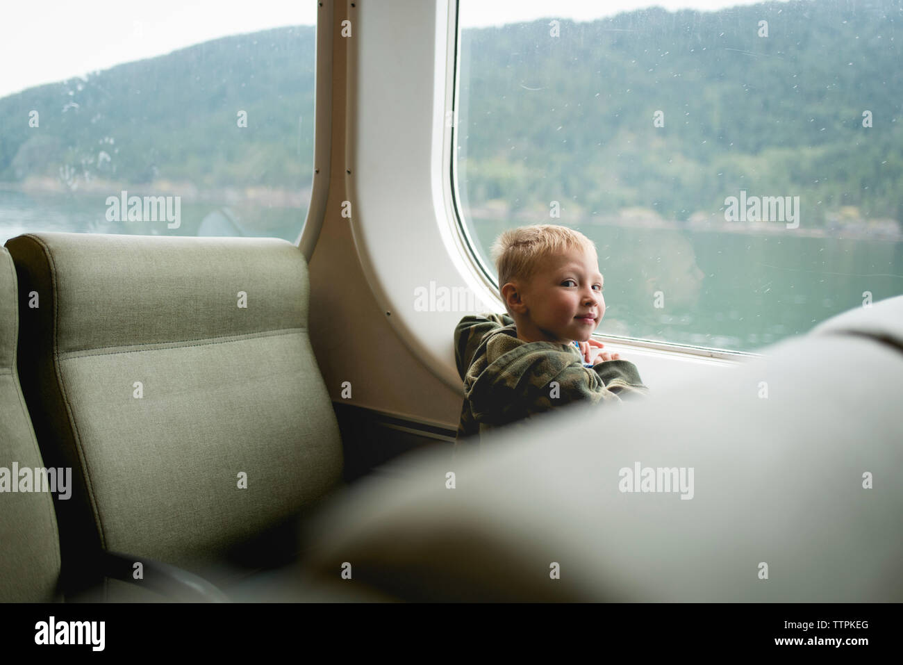 Ritratto di ragazzo seduto dalla finestra mentre si viaggia in treno Foto Stock