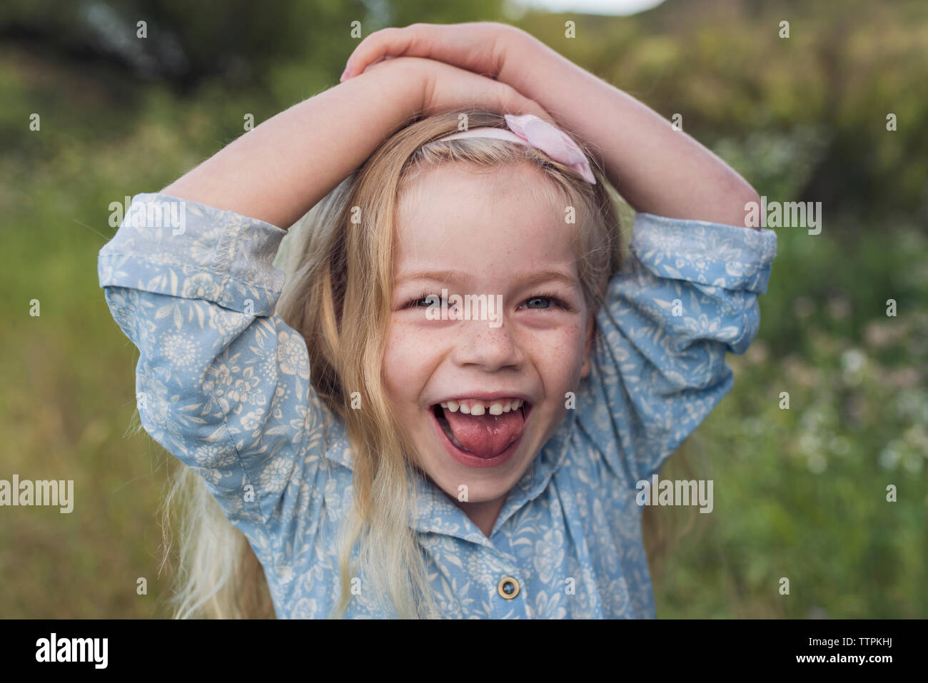 Ritratto di felice ragazza con le mani sulla testa in piedi in posizione di parcheggio Foto Stock