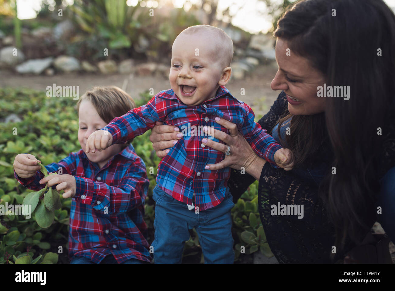 Azienda madre allegro bambino mentre il figlio a giocare con le piante in posizione di parcheggio Foto Stock