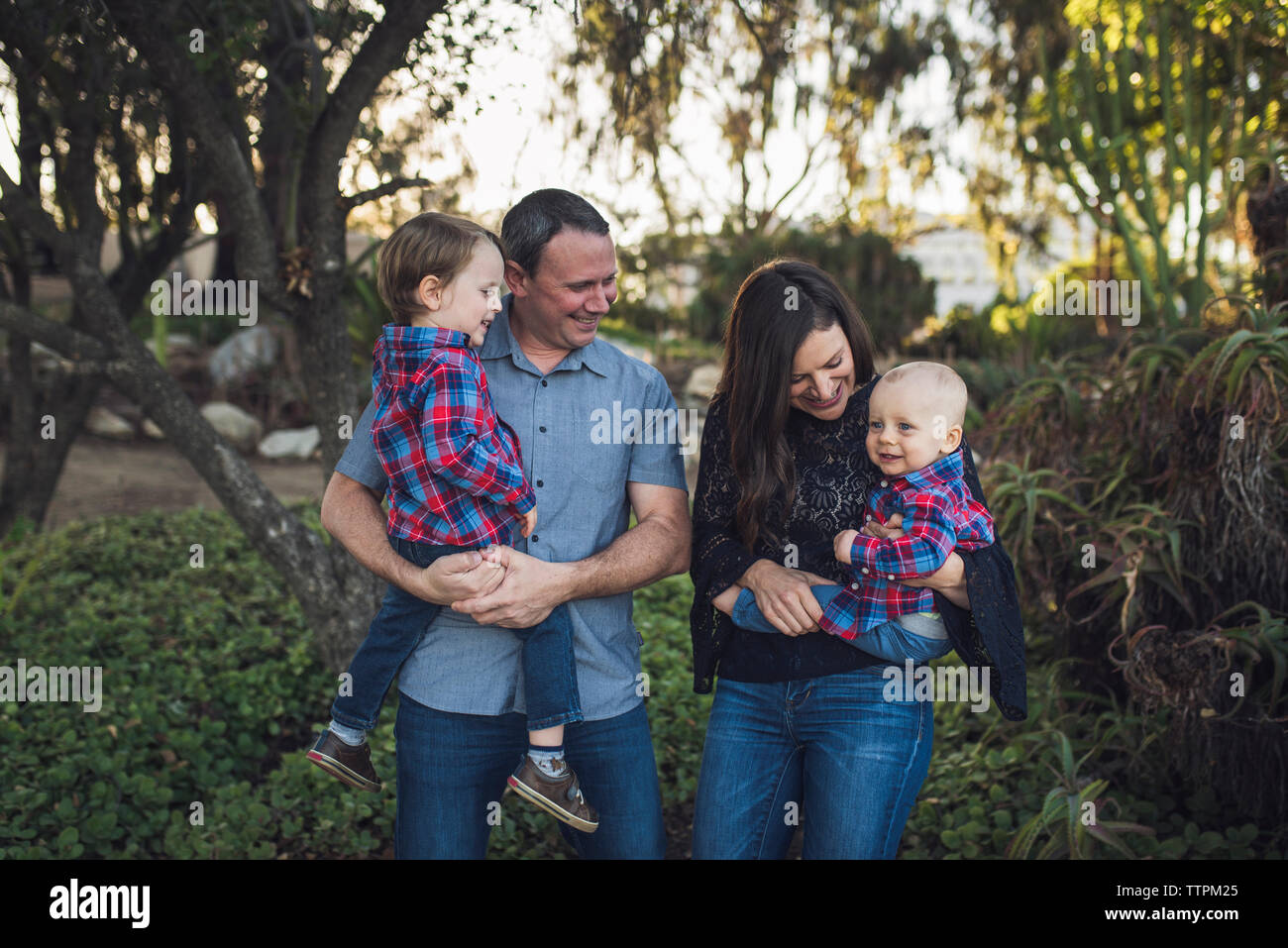 Genitori felici che trasportano figli rimanendo in posizione di parcheggio Foto Stock