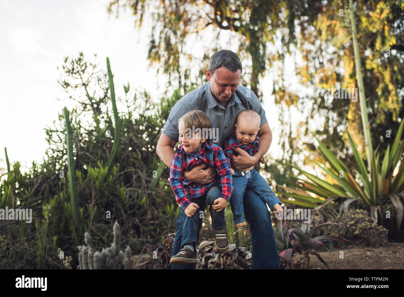 Padre giocoso che trasportano figli mentre giocando con loro in posizione di parcheggio Foto Stock