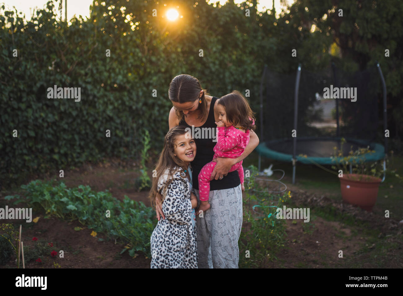 Madre con le figlie in piedi in cantiere durante il tramonto Foto Stock