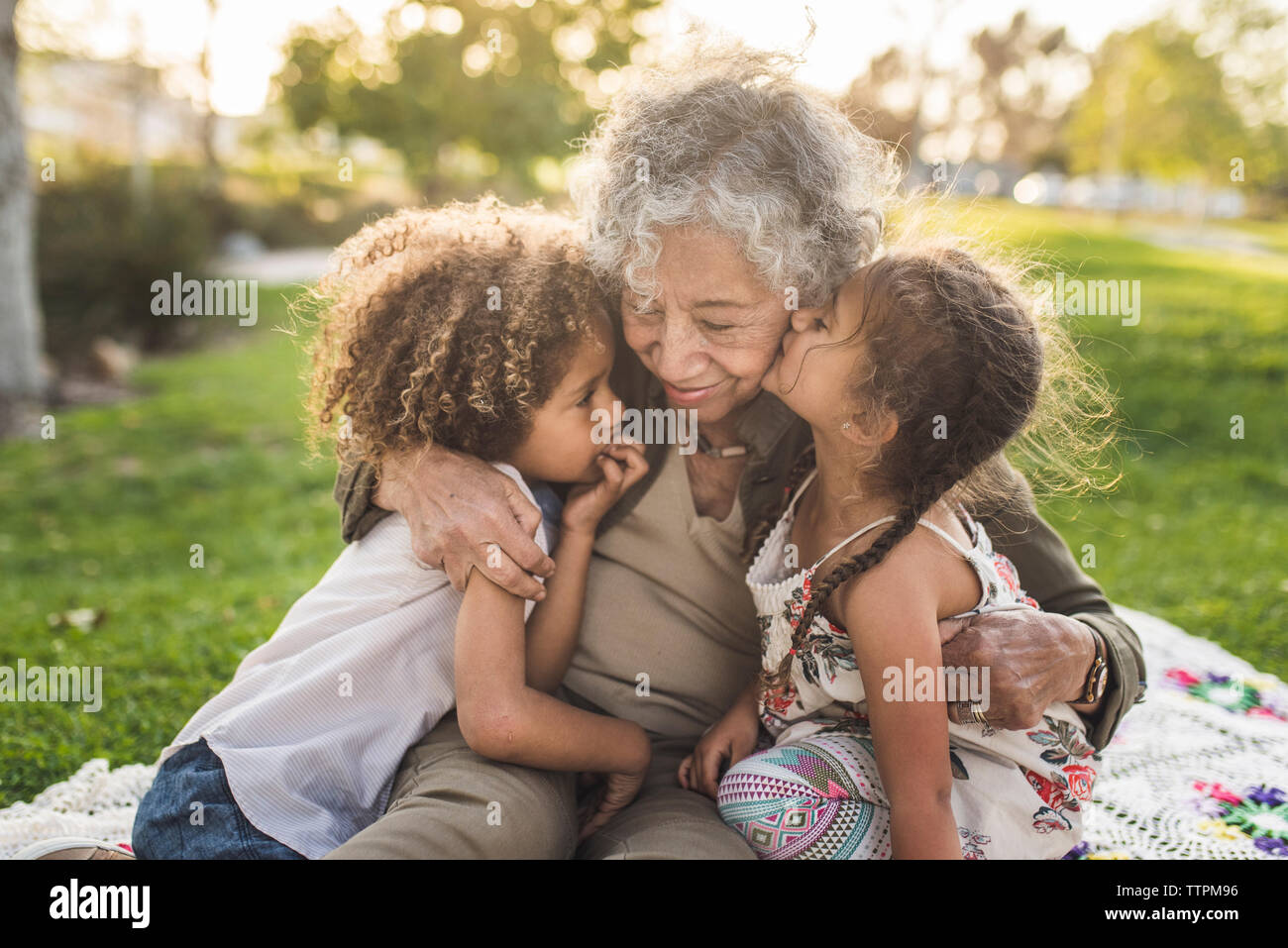 Nipoti con la nonna sulla coperta picnic al parco Foto Stock