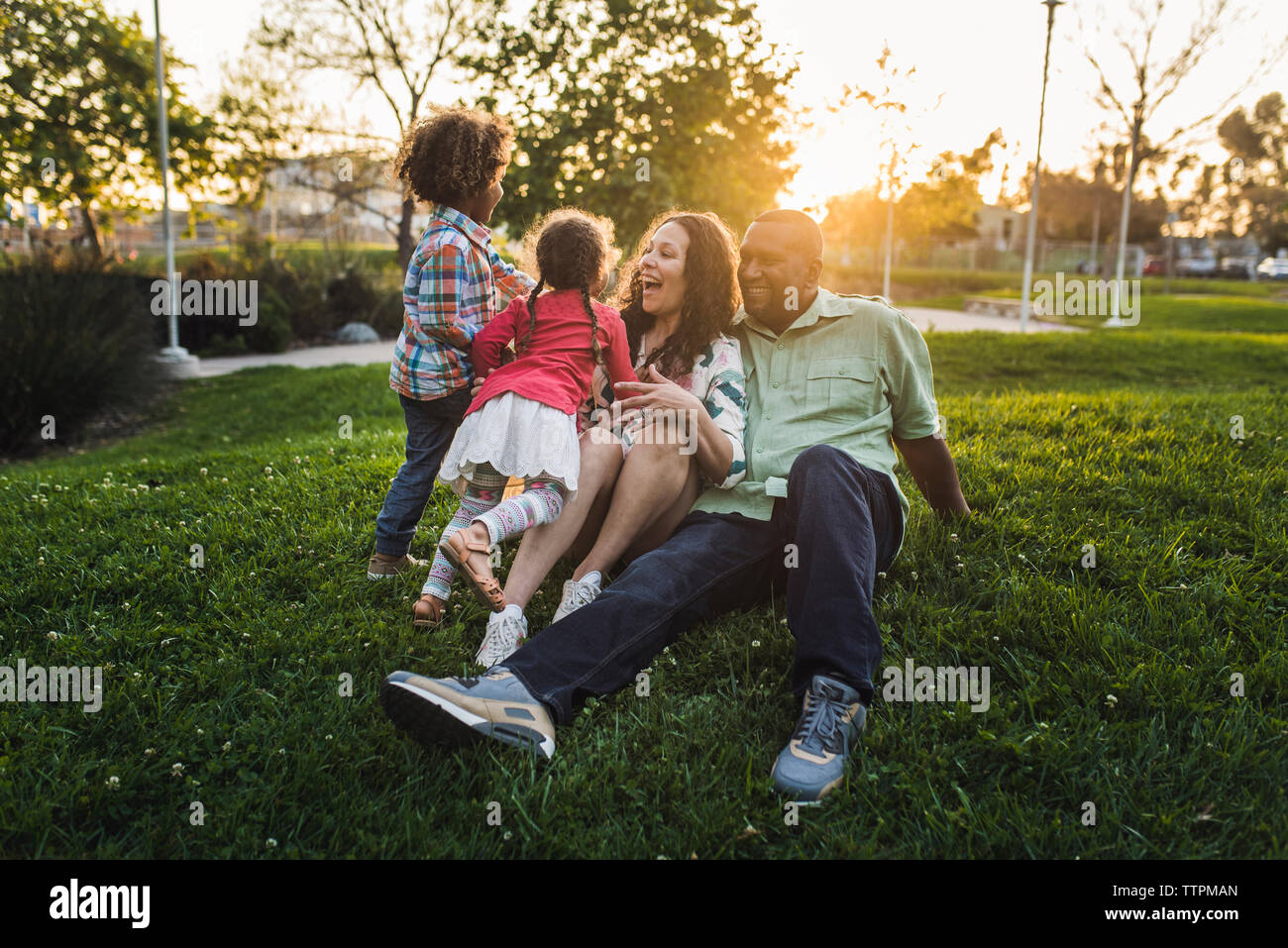 La famiglia felice a giocare sul campo erboso a park durante il tramonto Foto Stock