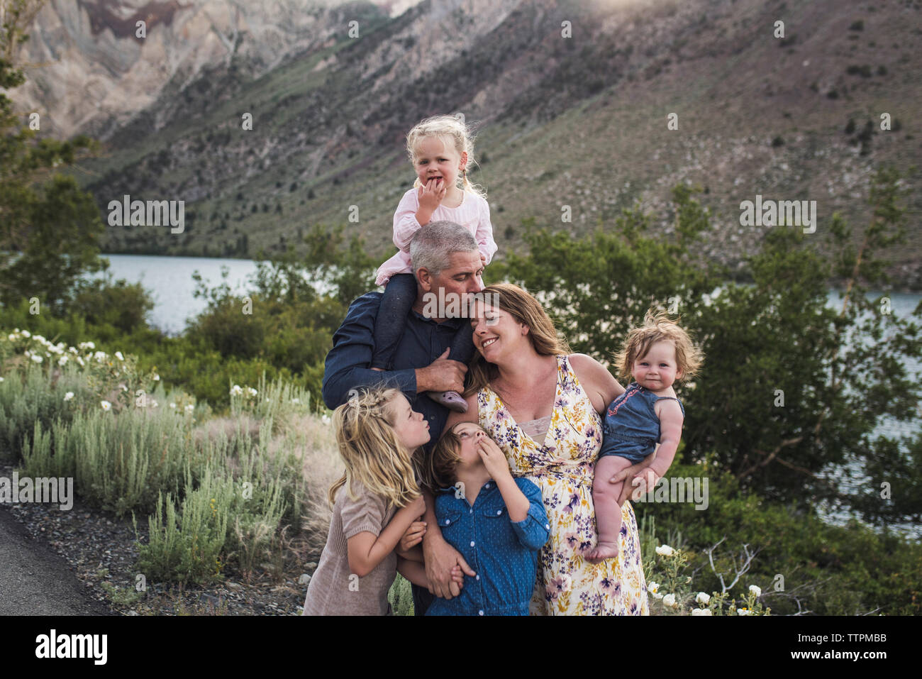 Romantico genitori con graziosi figlie in piedi contro la montagna in foresta Foto Stock
