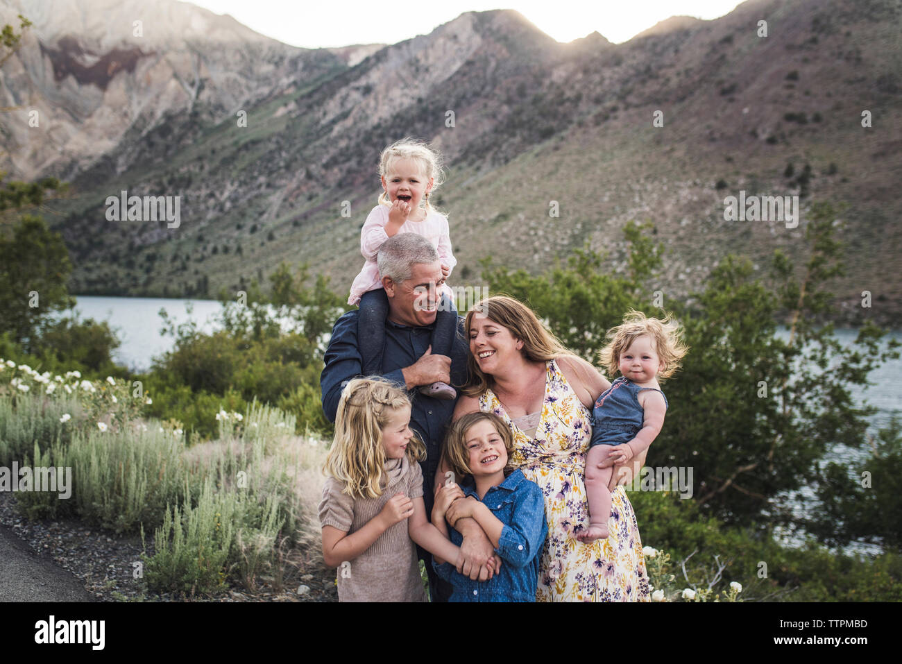 Genitori felici con graziosi figlie in piedi contro la montagna in foresta Foto Stock