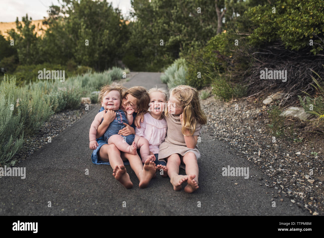 Felice carino sorelle seduti su strada nella foresta Foto Stock