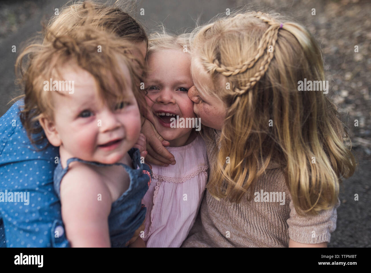 Angolo di alta vista di felice cute ragazze kissing sorella seduti su strada nella foresta Foto Stock