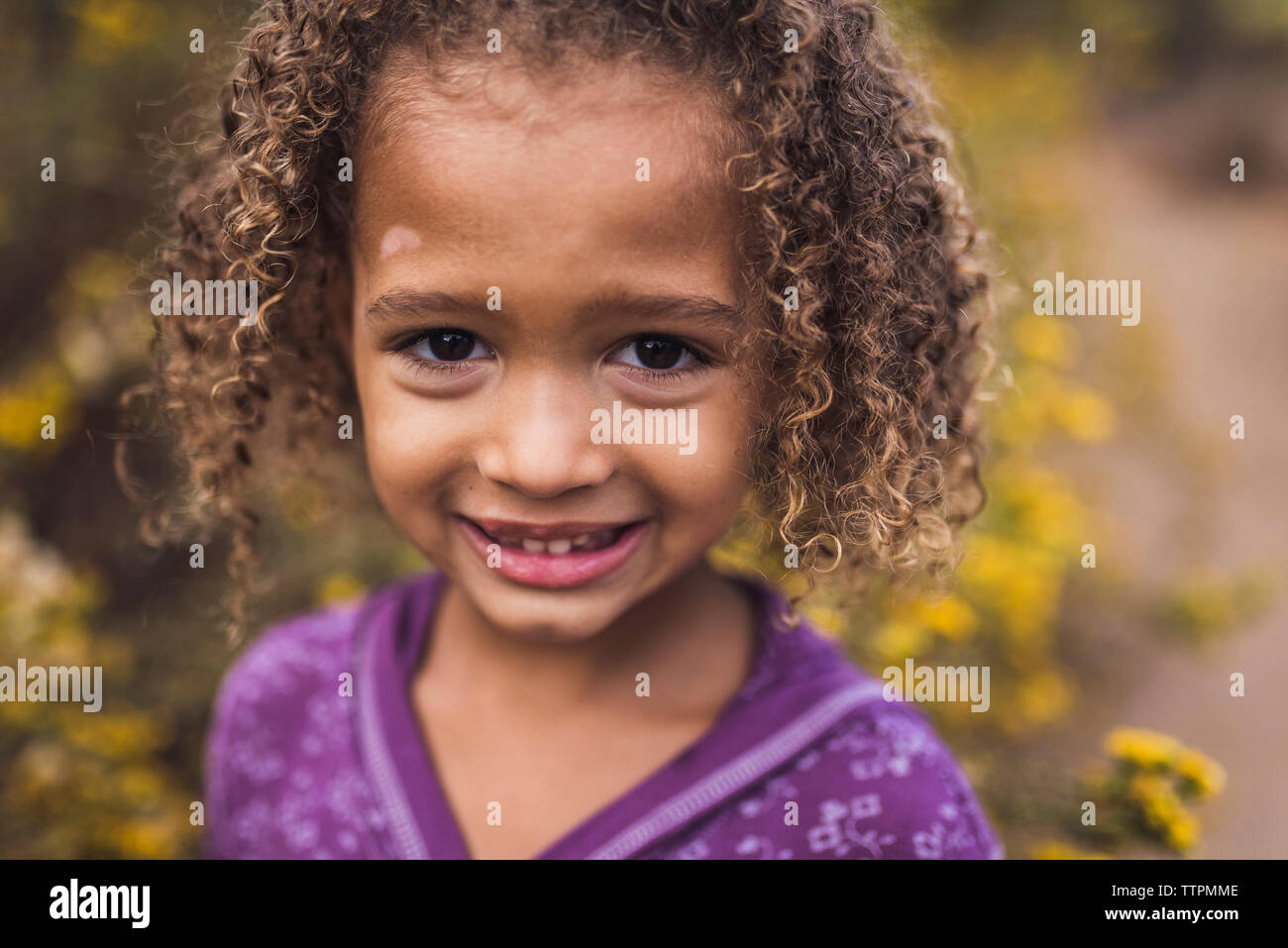 Close-up ritratto di sorridente ragazza con i capelli ricci in piedi in posizione di parcheggio Foto Stock