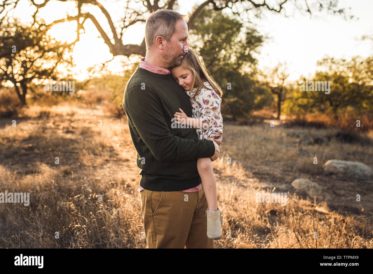 Figlia di essere abbracciati dal padre nel campo della California durante il tramonto Foto Stock