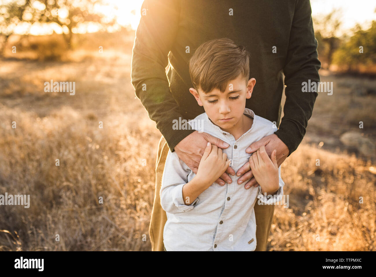 Chiusura del giovane ragazzo essendo abbracciato dal padre nel campo della California Foto Stock