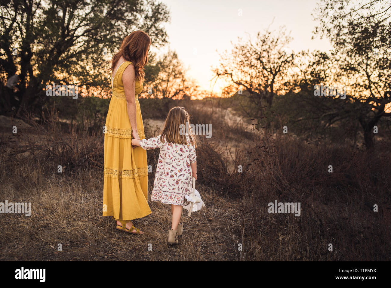 Ragazza giovane azienda madri mano mentre a piedi nel campo della California Foto Stock