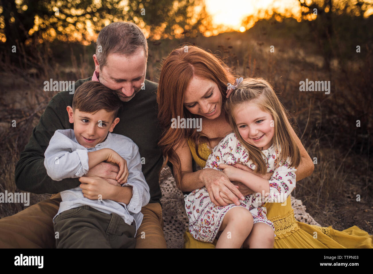 Famiglia giovane solletico ogni altro nel campo della California al tramonto Foto Stock