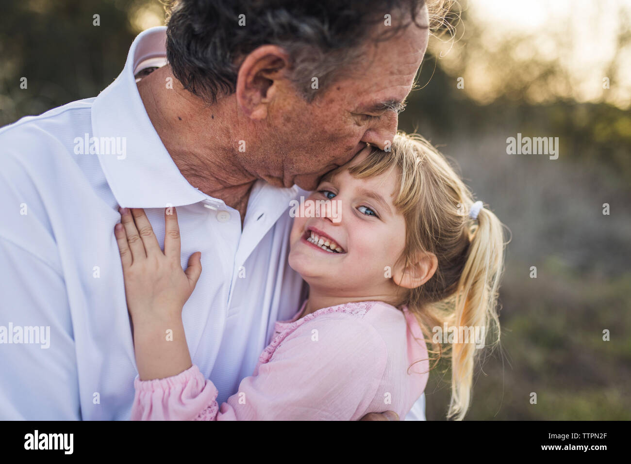 Nonno abbracciando giovane nipote e la bacia sulla fronte Foto Stock