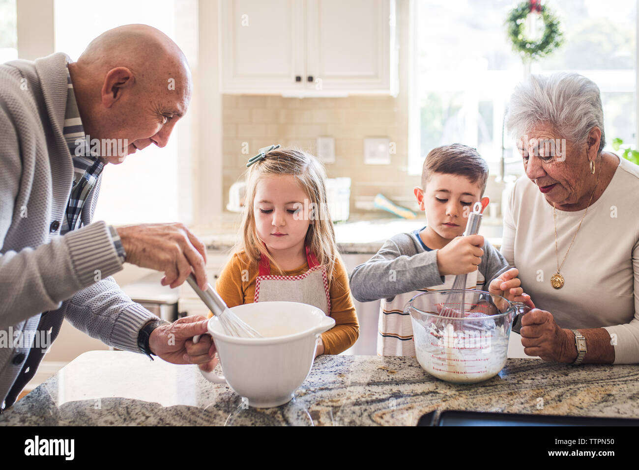 Famiglia multigenerazionale frittelle di cottura per la prima colazione Foto Stock