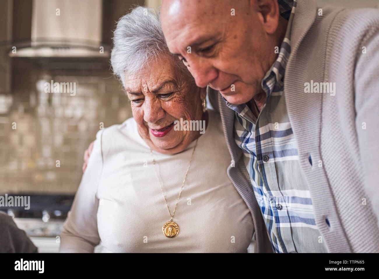 In prossimità del figlio adulto abbracciando il senior madre in cucina Foto Stock