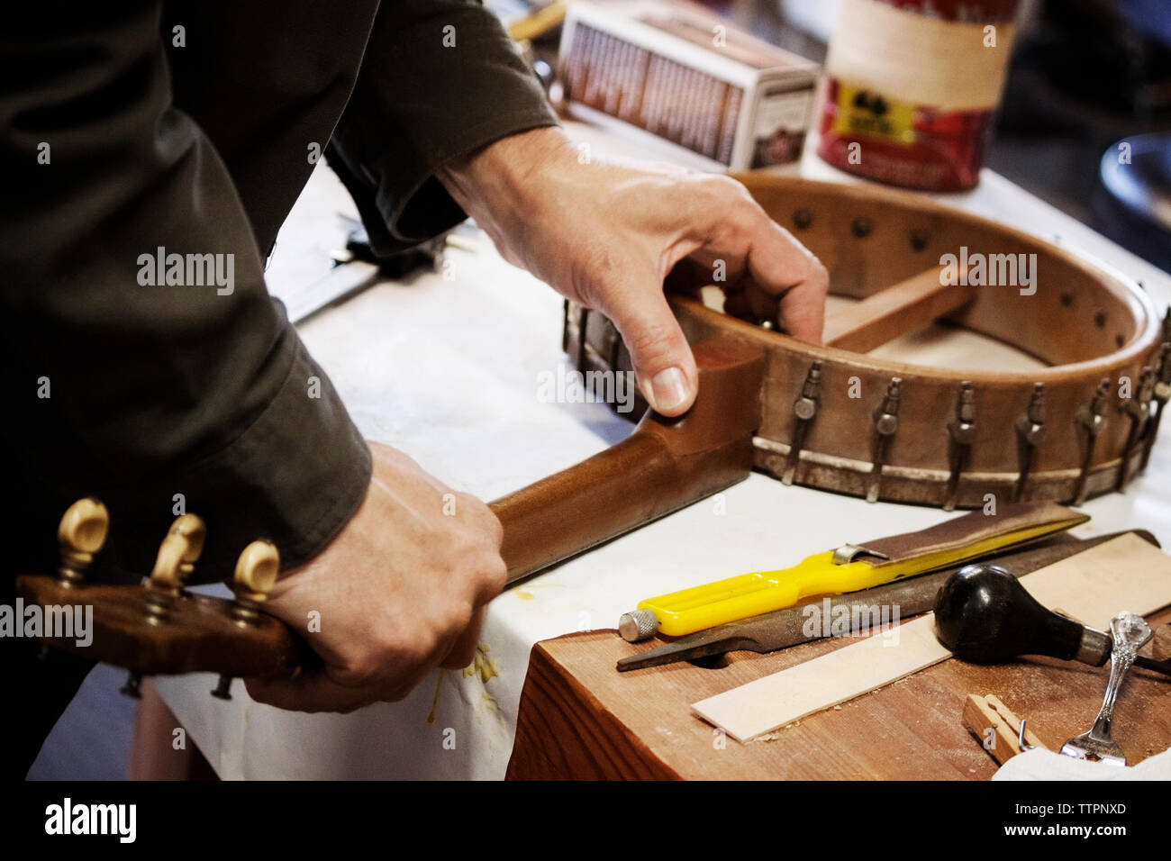 Immagine ritagliata dell'uomo facendo attrezzature musicali sulla tavola in officina Foto Stock