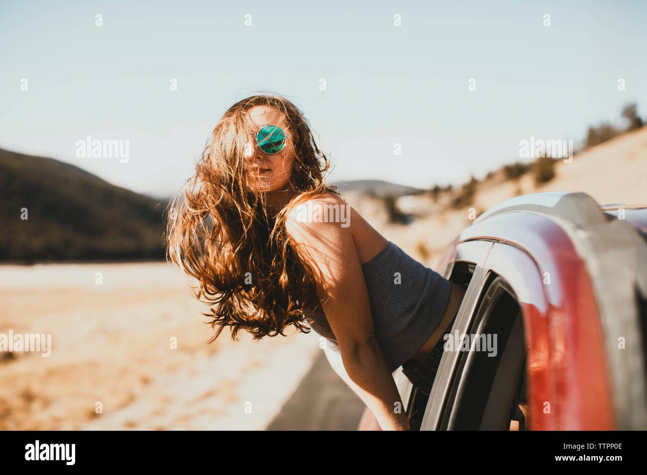 Vista laterale della giovane donna con capelli tousled sporgersi dal finestrino Foto Stock