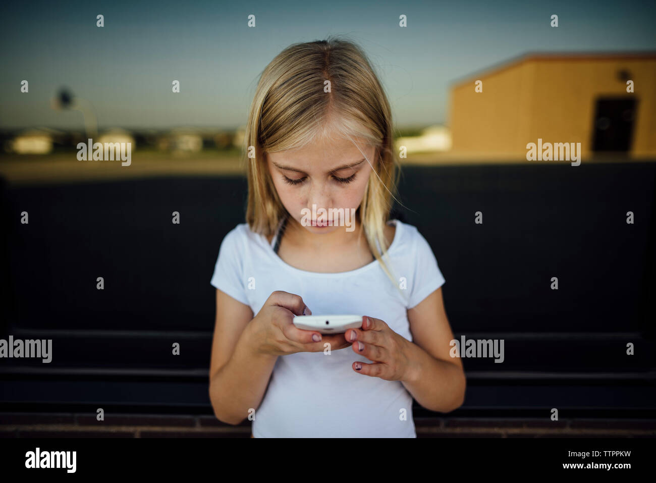 Ragazza utilizzando il telefono cellulare mentre in piedi contro la costruzione di Foto Stock