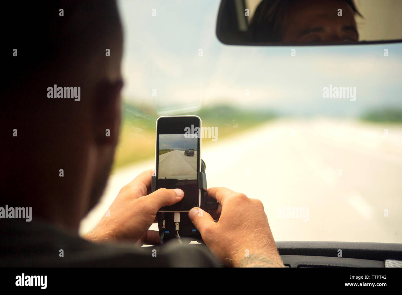 Uomo che utilizza il telefono cellulare mentre è seduto con un amico in auto Foto Stock
