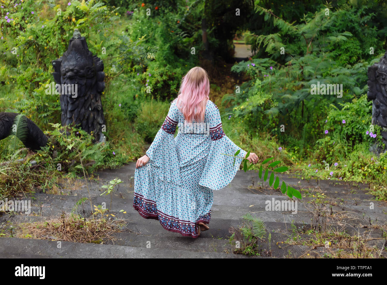Vista posteriore della donna nel vestire il movimento verso il basso sulle fasi a forest Foto Stock