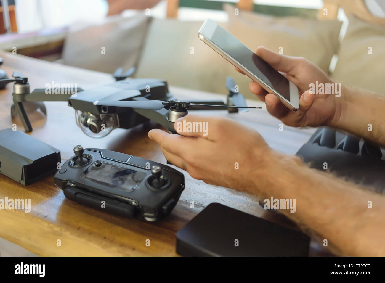 Mani tagliate di ingegnere usando il cellulare mentre esaminando quadcopter sul tavolo in ufficio Foto Stock