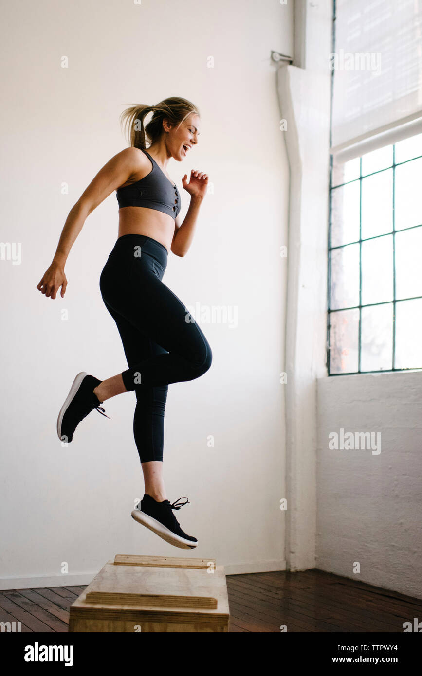 Atleta femminile urlando saltando su una scatola di legno in palestra Foto Stock