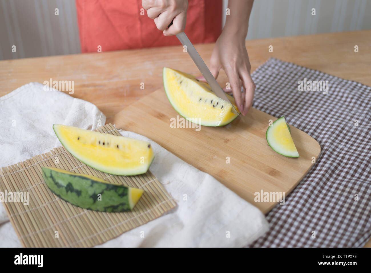 Tagliate le mani della donna anguria di taglio sul tavolo a casa Foto Stock