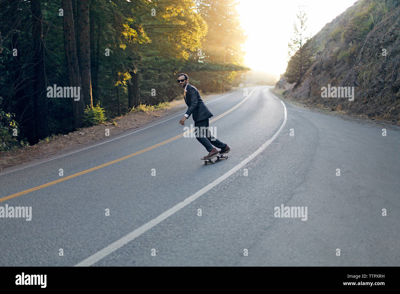 skateboard da uomo d'affari in strada nelle giornate di sole Foto Stock