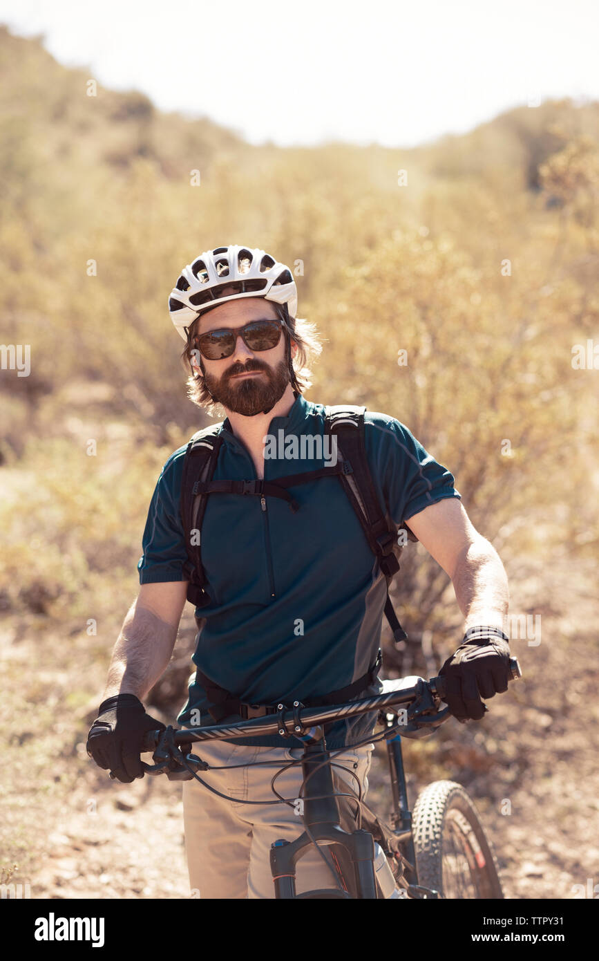 Ritratto di fiducioso biker in piedi con la bicicletta in montagna Foto Stock