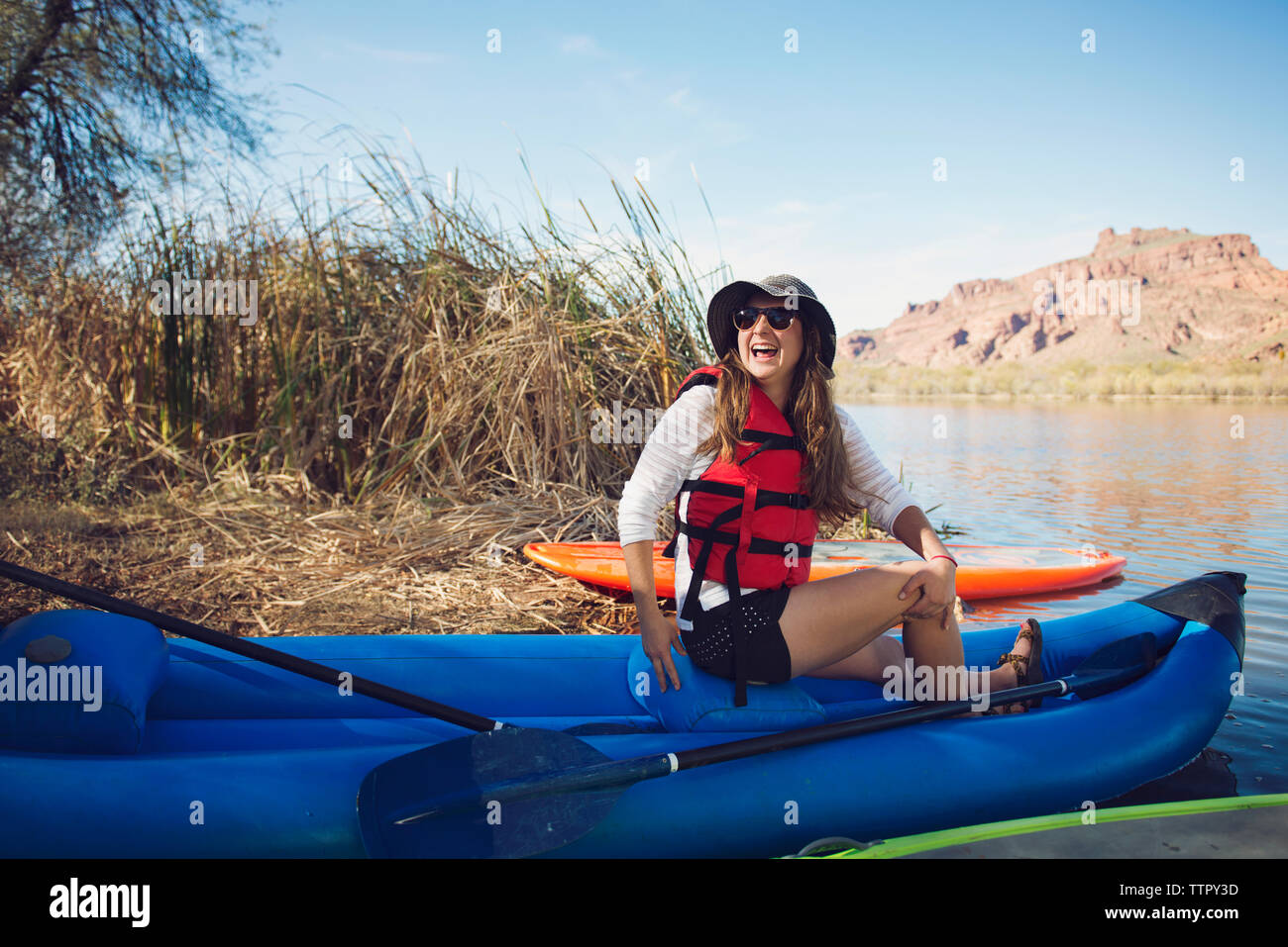Donna felice che guarda lontano mentre è seduto sul kayak gonfiabili sul lungolago Foto Stock