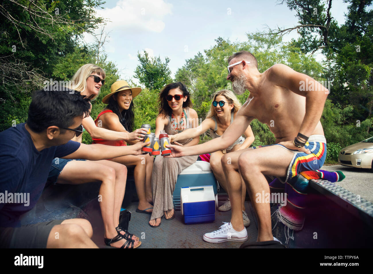 Amici di bevande di tostatura mentre sedendo nel pick-up Foto Stock