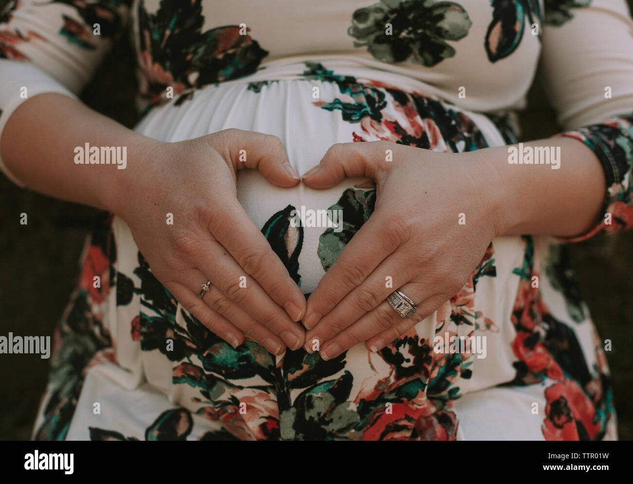 Sezione mediana della donna incinta messa a forma di cuore sul suo ventre con le mani Foto Stock