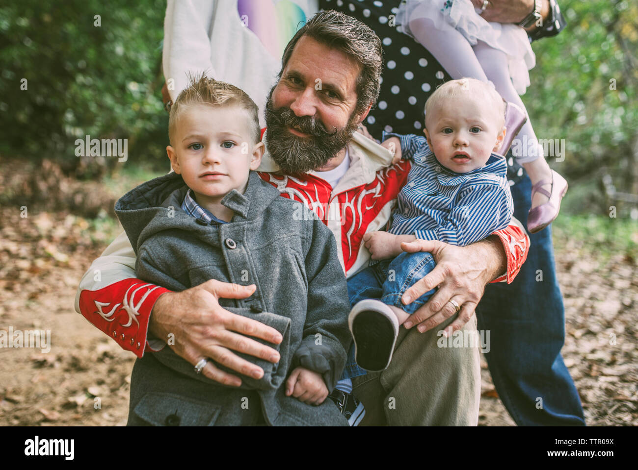 Ritratto di uomo e i bambini contro la famiglia sul campo al park Foto Stock