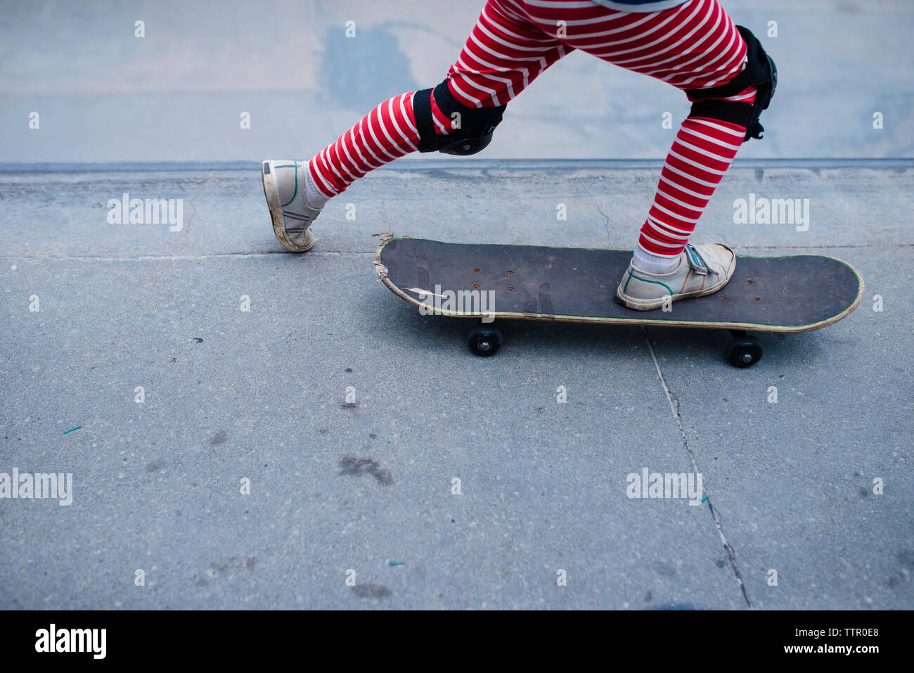 Sezione bassa di boy skateboarding sport sulla rampa di skate park Foto Stock