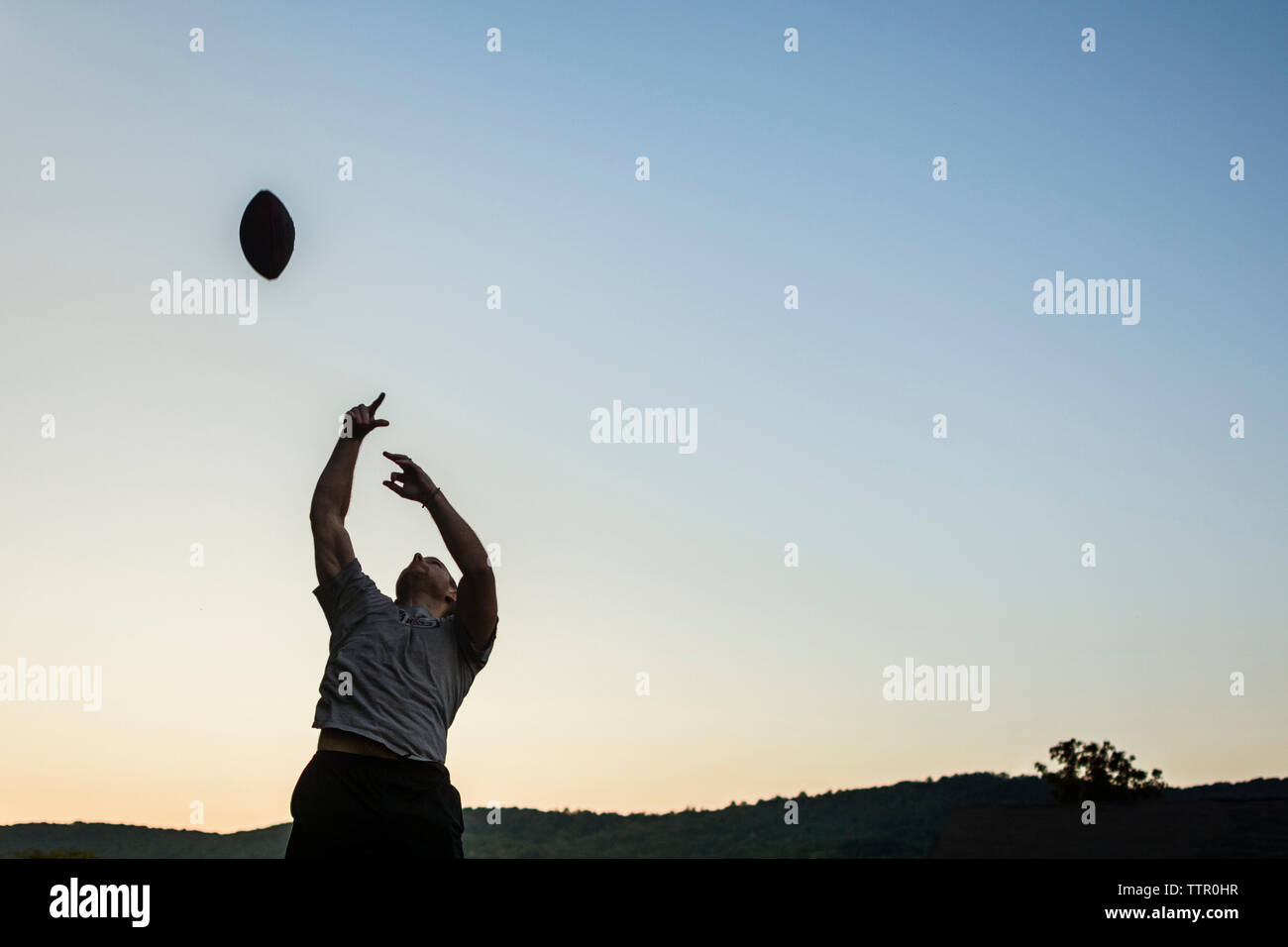 Basso angolo di visione dell uomo che giocano a calcio contro il cielo chiaro durante il tramonto Foto Stock
