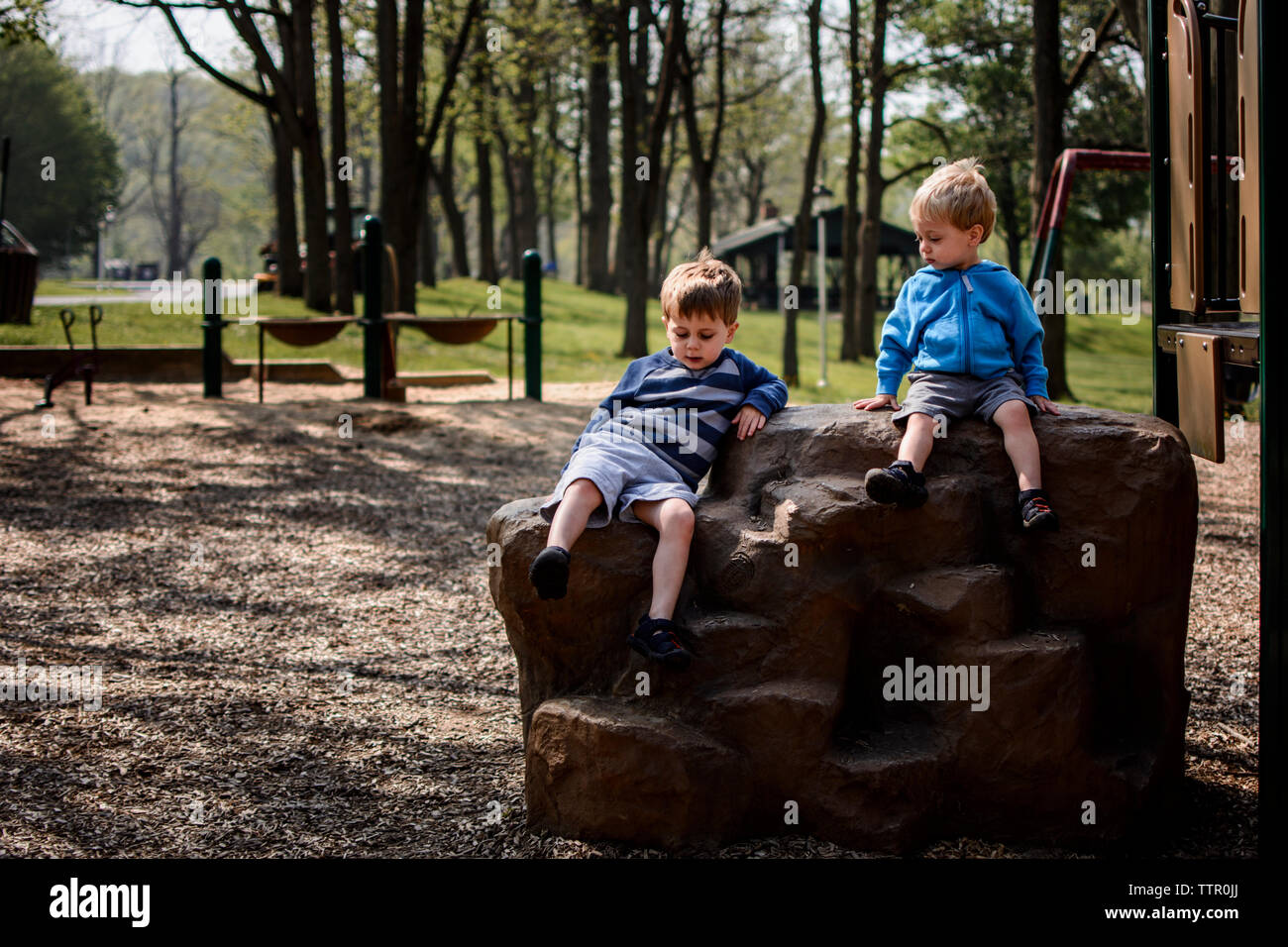 Fratelli seduti sulla roccia nel parco giochi Foto Stock