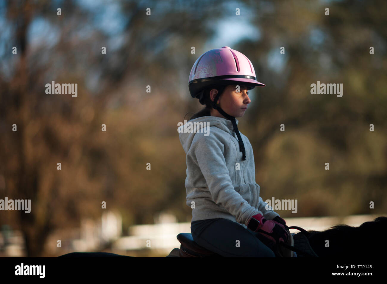 Vista laterale della ragazza a cavallo nel ranch Foto Stock