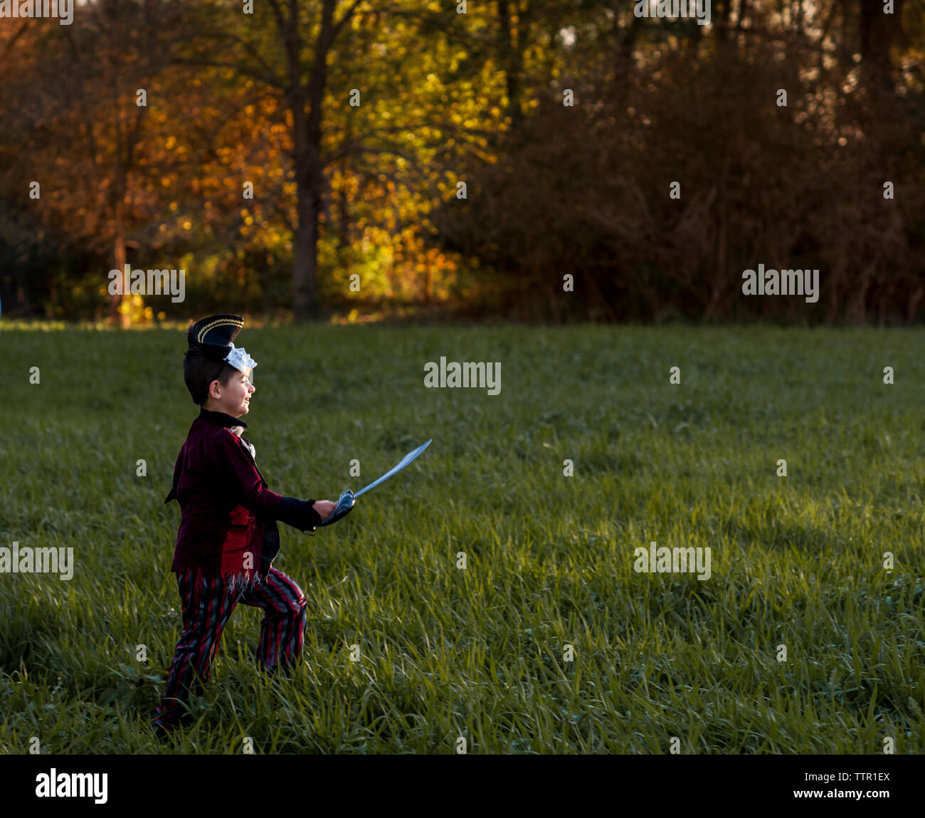 Vista laterale del ragazzo giocoso indossando il costume di Halloween mentre si cammina sul campo erboso a park Foto Stock