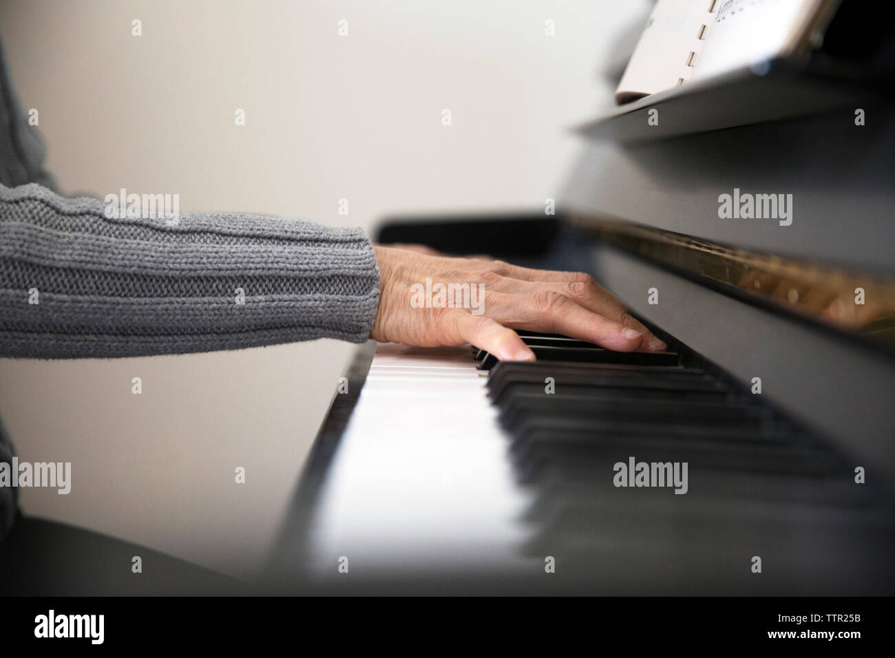 Immagine ritagliata della donna senior di suonare il pianoforte a casa Foto Stock