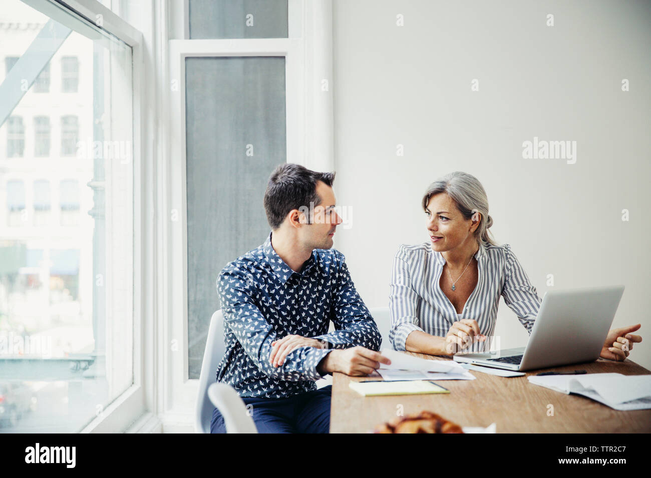 uomo d'affari e donna d'affari che discutono con un computer portatile in sala riunioni Foto Stock