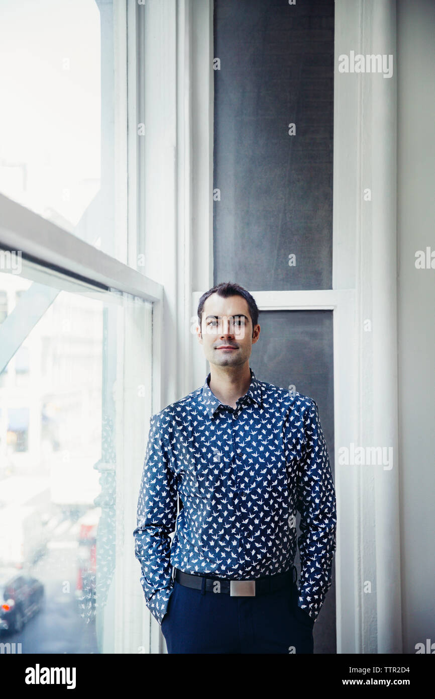 Ritratto di imprenditore fiducioso in piedi dalla finestra in ufficio creativo Foto Stock
